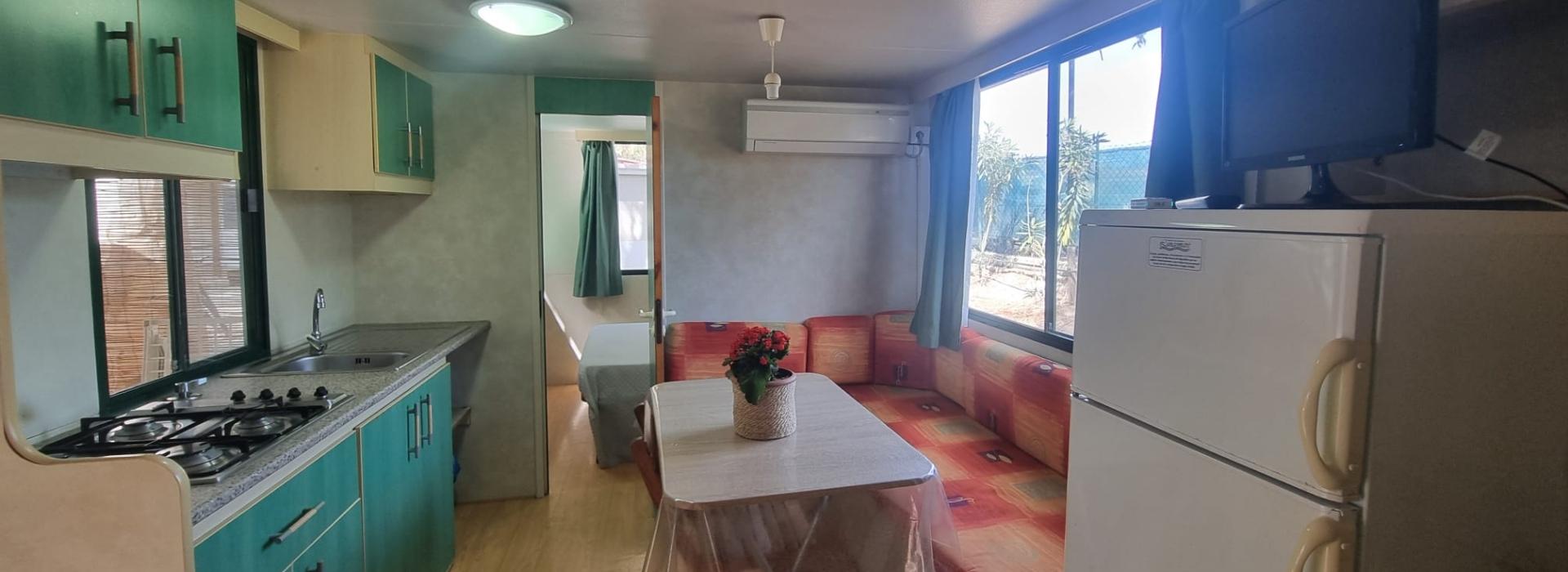 Interno di una casa mobile con cucina, tavolo e divano colorato.