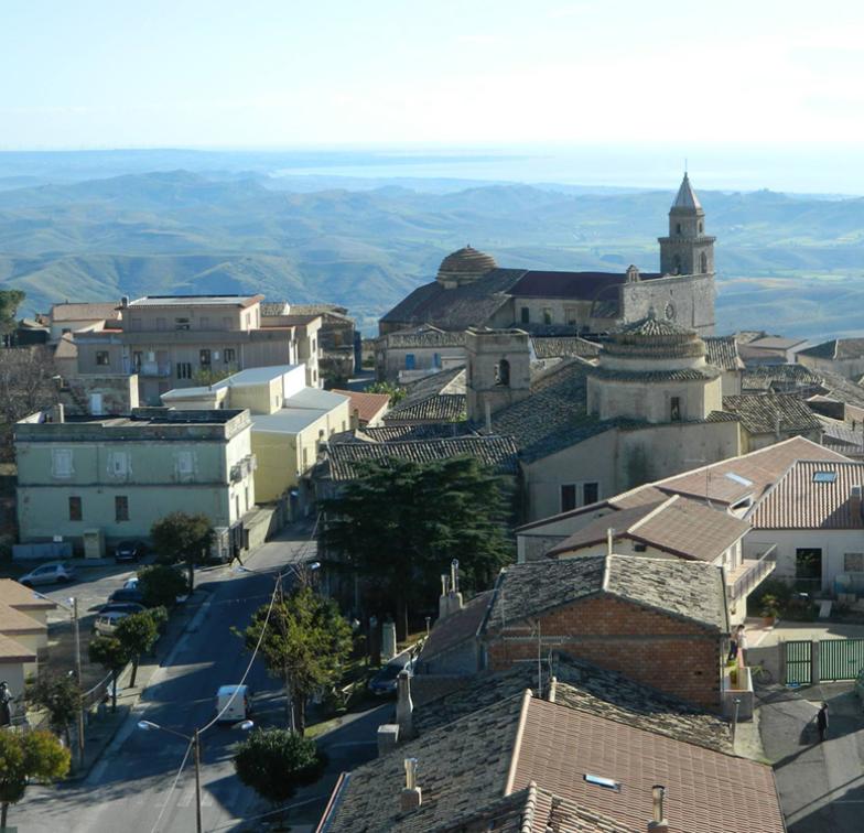 Paesaggio collinare con chiesa e case antiche.